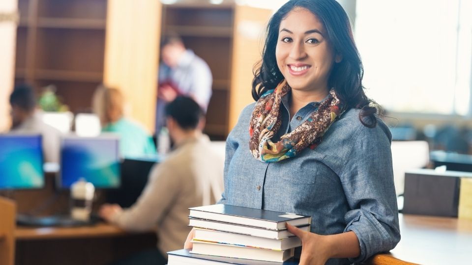 Woman carrying books in a library